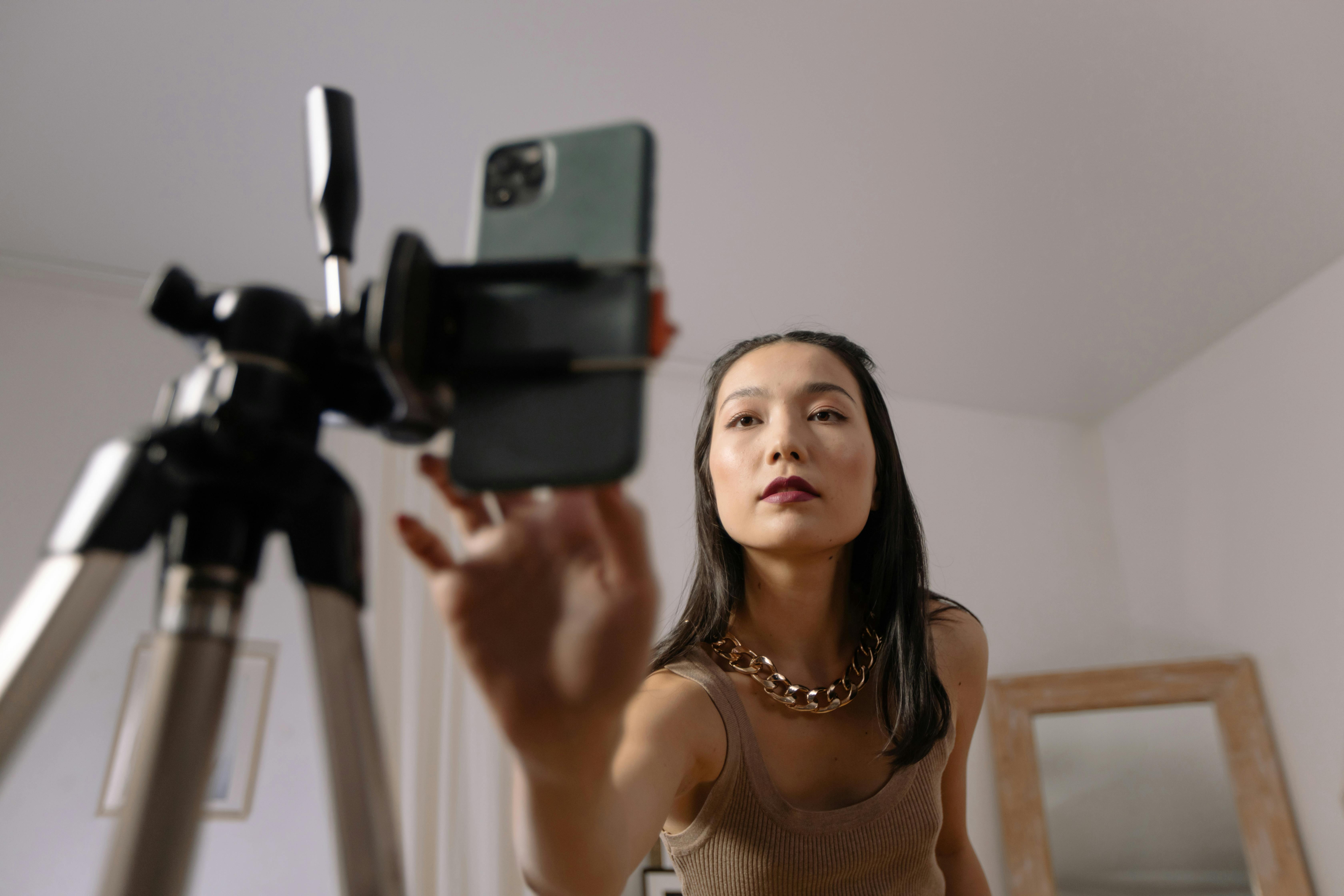 Young woman preparing to record content on her smartphone using a tripod, representing a social media influencer setup