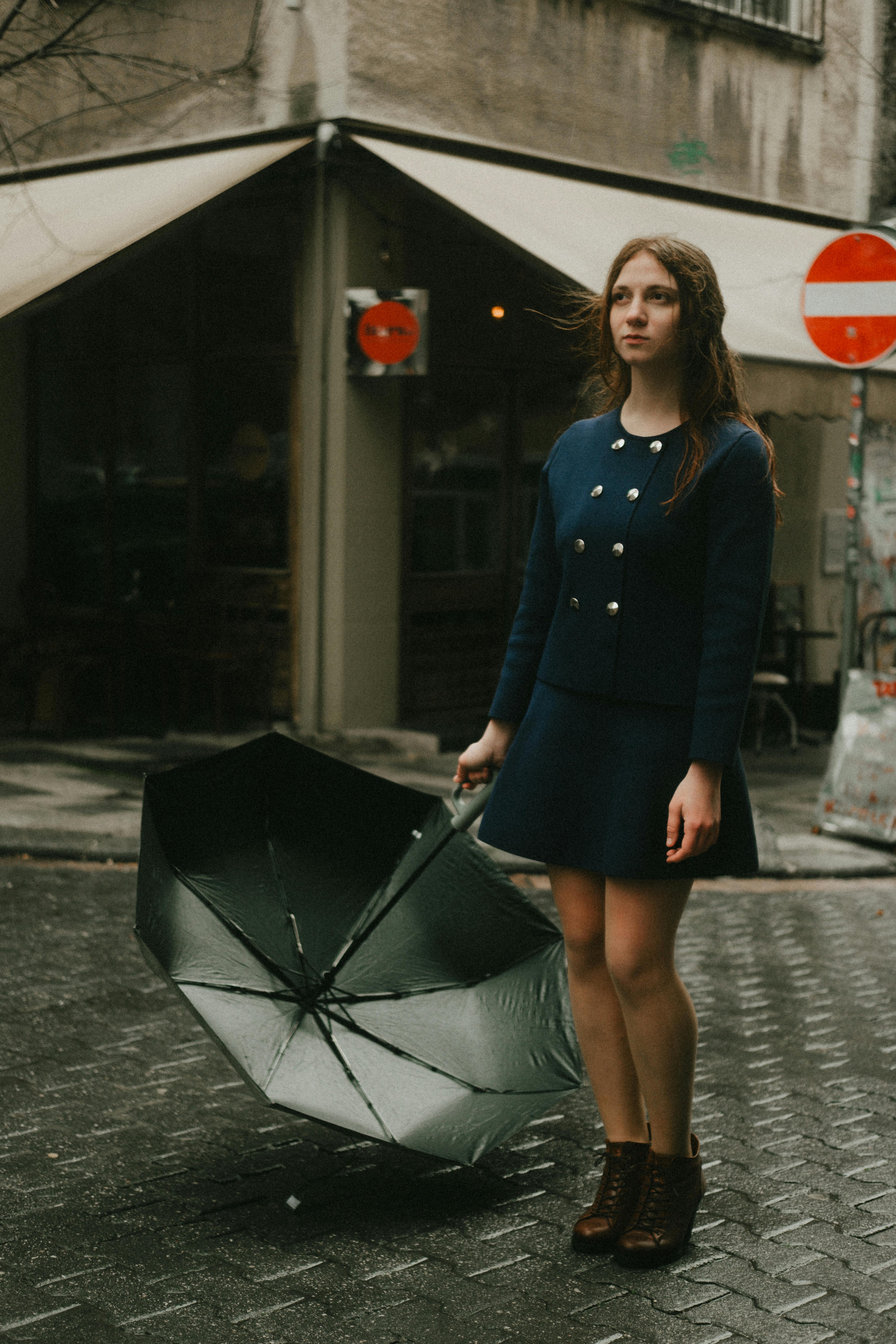 Young woman in a navy dress with umbrella, embodying the dark academia fashion trend