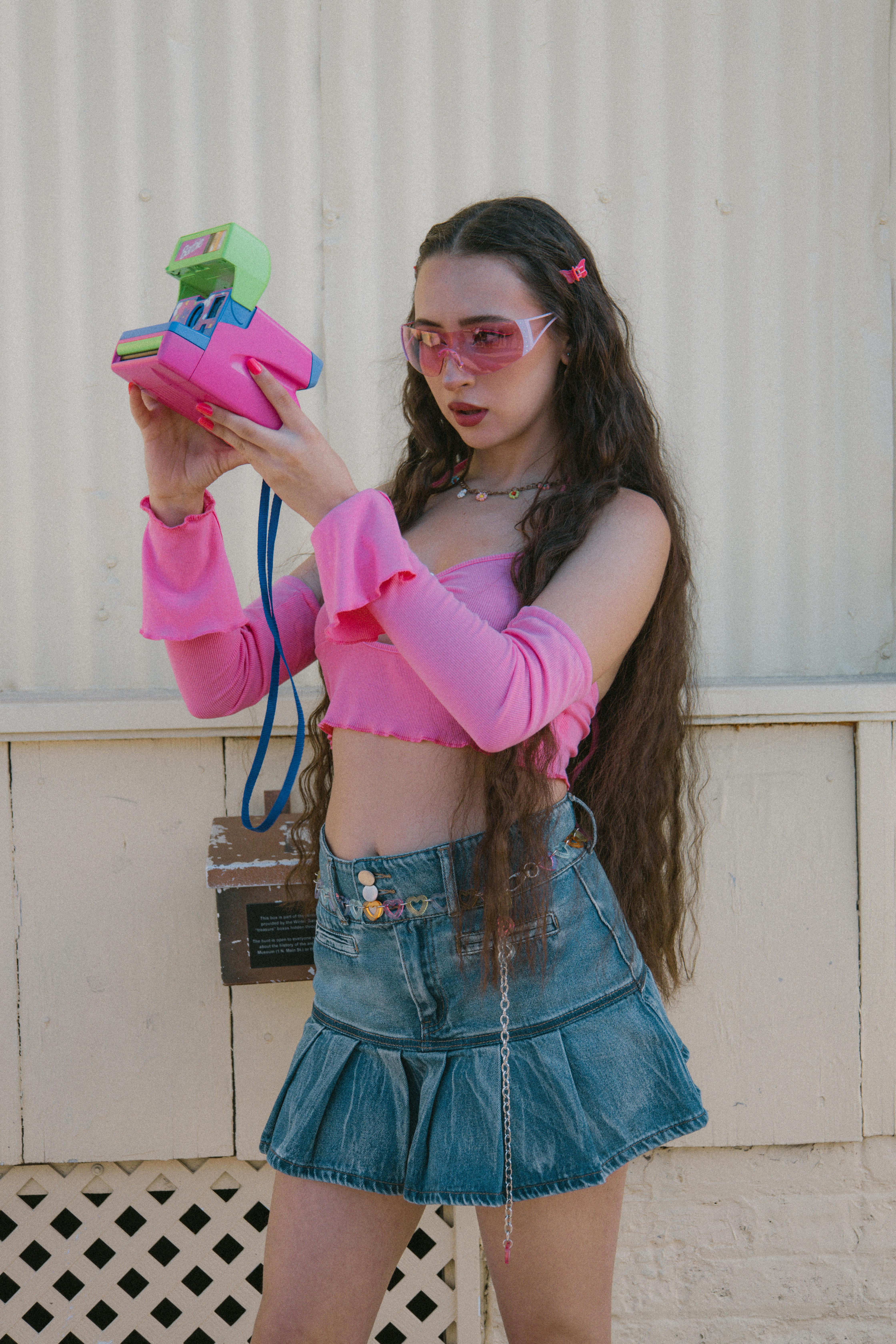 Young girl in bright pink crop top and denim mini skirt, capturing the bold and playful Y2K fashion aesthetic