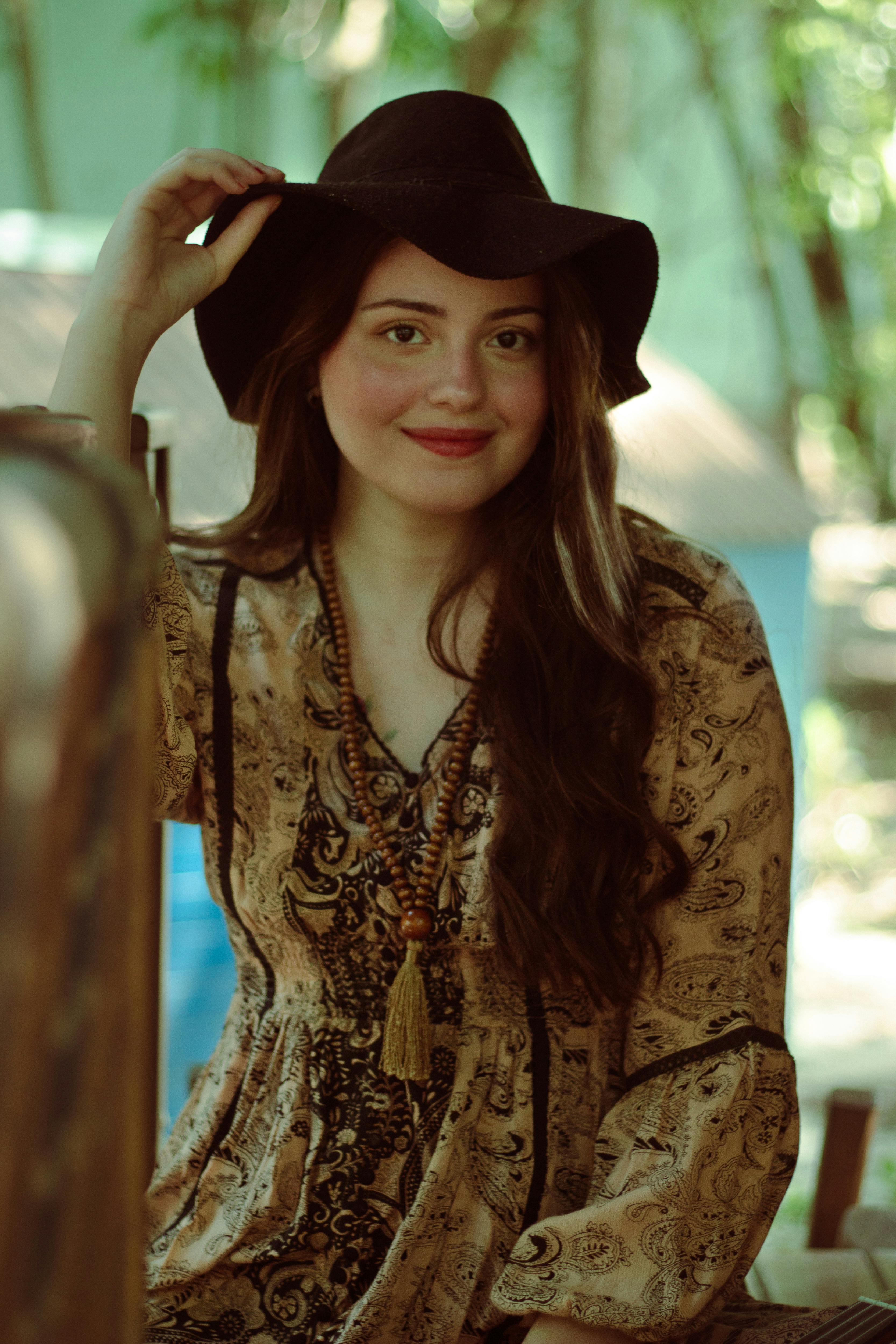 Woman in a flowy vintage dress and black hat, symbolizing the soft, nature-inspired Cottagecore aesthetic
