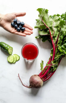 Fresh blueberries, cucumber slices, beetroot, and a glass of red juice, representing healthy vegetarian foods
